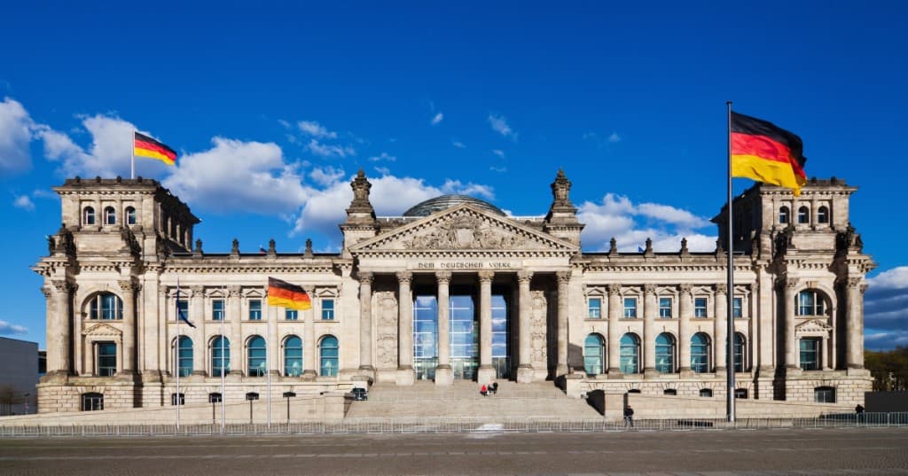 Berlin Reichstag binası ve Alman bayrakları — Almanya vize ve oturum rehberi