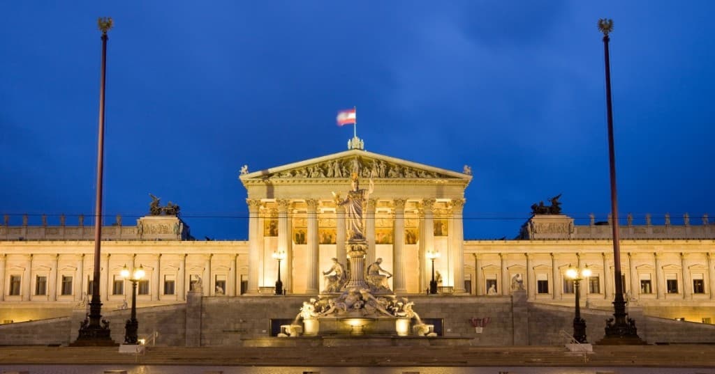 Viyana: Parlamento binası gece aydınlatması, önde Pallas Athena çeşmesi ve sütunlu cephe.