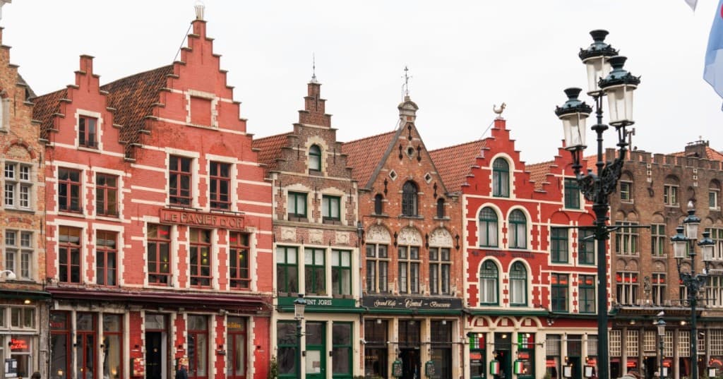 Brugge’de geleneksel Flaman cepheleri, merdiven alınlıklar ve kaldırımlı sokak — Belçika rehberi