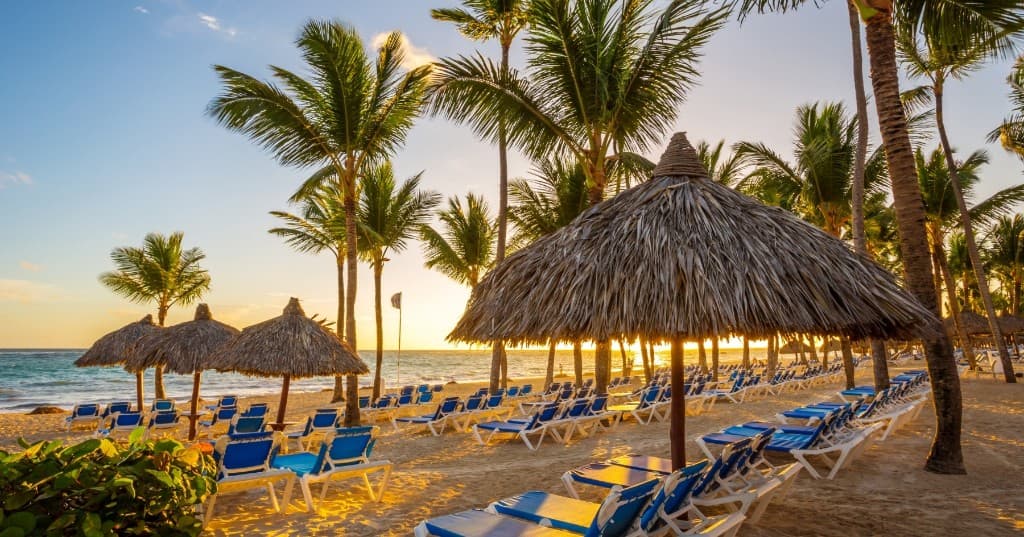 Punta Cana resort sahili, şezlonglar ve palmiyeler, gün doğumu ışığı