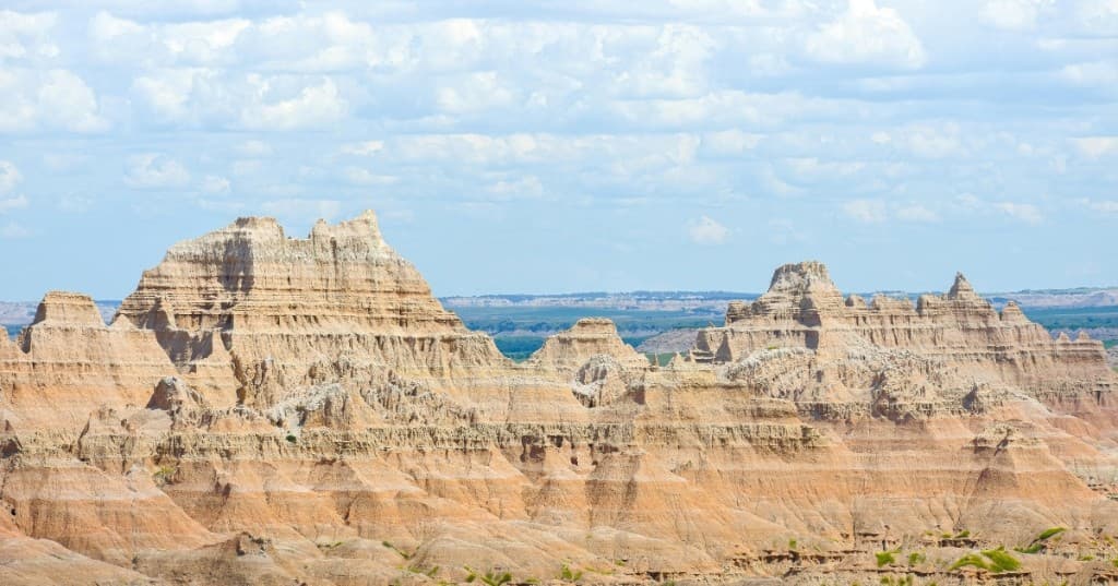 Kıbrıs iç kesimleri: yatay tabakalı açık renkli kayalıklar ve üzerinde beyaz bulutlu geniş gökyüzü.
