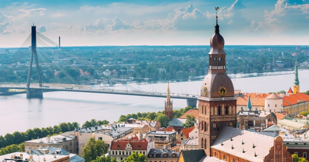 Letonya’nın başkenti Rīga: Vecrīga kırmızı kiremit çatıları, Rīgas Doms kulesi ve Daugava üzerinde Vanšu tilts (kablolu köprü), açık mavi gökyüzü.