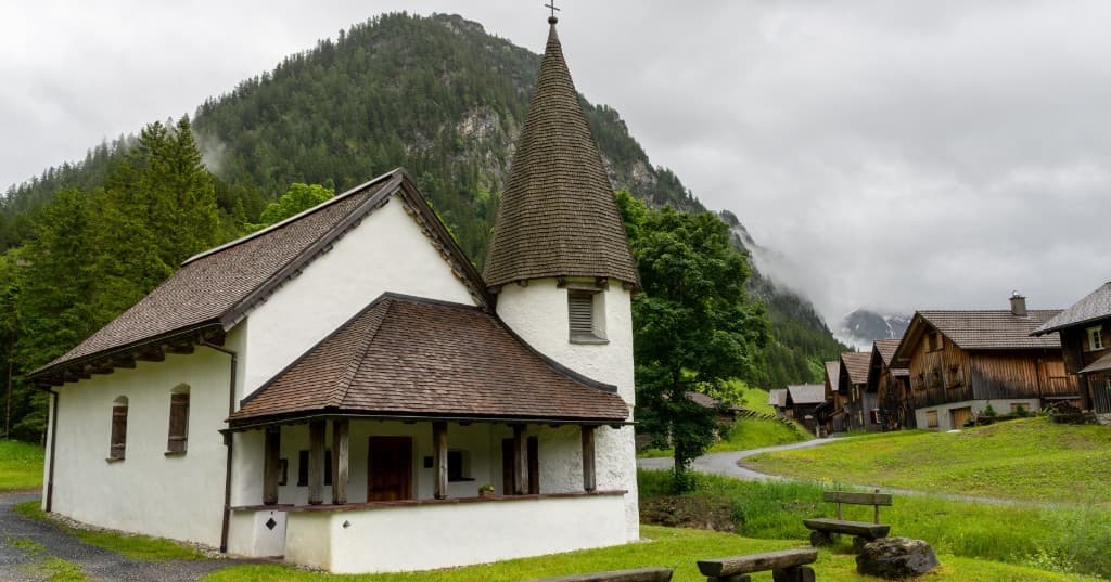 Vadili Alp manzarasında beyaz şapel ve ahşap chalet sırası