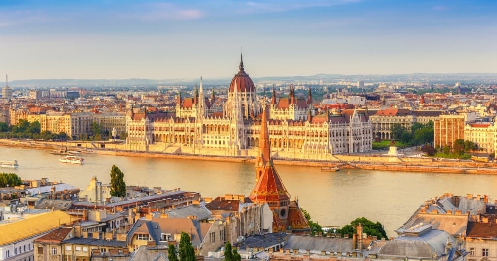 Budapeşte: Macaristan Ulusal Meclisi neo-Gotik cephesi ve Tuna üzerinde gün batımı ışığı.